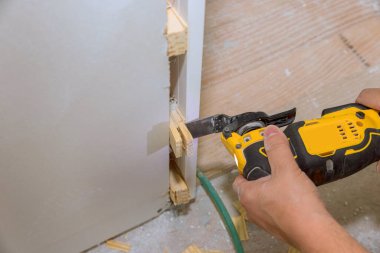 İşçi, kurulum kapısı inşaatı sırasında inşaat sırasında ahşap parçaları kesmek için el bilgisayarı kullanıyor..