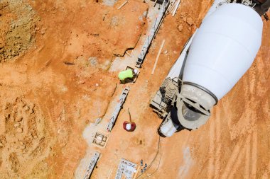 İnşaat alanındaki temel hazırlama görüntüsü, beton karıştırıcı kamyonun temel formları boyunca beton döşemesi