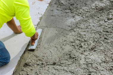 İşçi giysisi, inşaat alanında yeni dökülen beton aktiviteleri yumuşatmak için mala kullanıyor