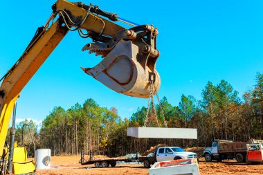 Konut inşaatı sırasında büyük kazıcı inşaat alanındaki beton bloğu kaldırıyor