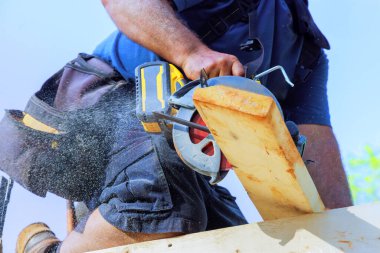 Marangoz inşaat alanında elektrikli testereyle ahşap kirişi ustalıkla kesiyor.