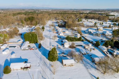 Sakin kış ortamında, karlı Amerikan banliyö manzarası binaların, yolların, huzurlu kış atmosferinin olduğu mahalleleri gösteriyor.
