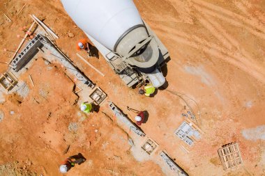 İnşaat alanının görünümüne göre önceden belirlenmiş temel formları boyunca beton döşeyen beton karıştırıcı kamyon.