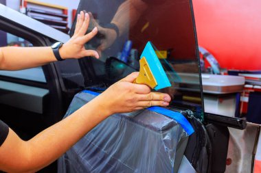 Teknisyen araba kapısına pencere boyası sürerken, aynı zamanda canlı oto tamir ortamında pürüzsüz bir bitiriş sağlıyor..