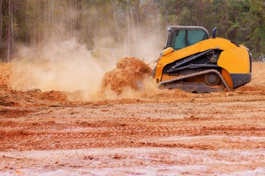 On construction site, bulldozer is leveling ground graded soil for preparing construction. clipart