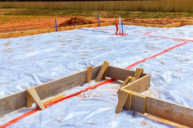 Alandaki yeni bina için temel hazırlanırken, ahşap çerçevelerle çevrili koruyucu plastikle kaplı bir alan da kullanılıyor.