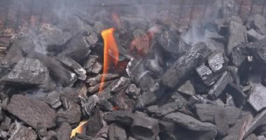 Kömür parçaları parlıyor, alevler yükselirken yanıyor, açık havada pişirme oturumunun sinyallerini veriyor..