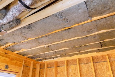 Yeni ev inşaatı sırasında enerji verimliliğini artırmak için ahşap yapıda korunmasız kirişler arasına izolasyon kuruluyor