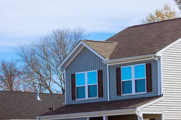 Gri kaplamalı, çoklu pencereli, Amerikan kasabasındaki banliyö banliyösünün altında kahverengi panjurlu banliyö evinin üst kısmının görüntüsü