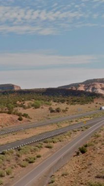 Kuru yol, New Mexico çöl arazisi boyunca uzak kaya oluşumları araçlarıyla yol boyunca seyahat ediyor..
