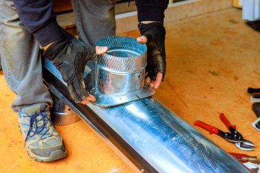 Yetenekli işçiler, atölyeye HVAC ısıtma sistemi için güvenli bağlantı sağlayan metal kanal montajı yapıyor..