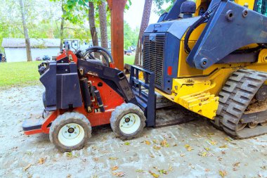İnşaat iskeleti tarama sırasında, çakıl yüzeyinde yan yana park edilmiş iki parça inşaat yükleyicisi var.