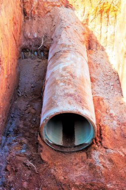 İşçi inşaat alanında büyük beton boruyla drenaj sistemi hazırlarken, borular beton döşüyordu.