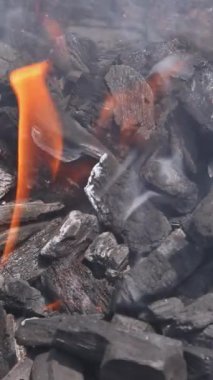 Kömür parçaları parlıyor, alevler yükselirken yanıyor, açık havada pişirme oturumunun sinyallerini veriyor..