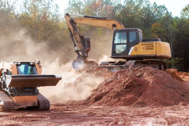 Kazıcılar ve yükleyiciler toprağı inşaat sahasına taşıyarak tozu geliştirmeye hazırlıyorlar..