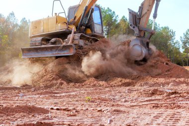 Büyük kazıcı inşaat alanında Dünya 'yı kazıyor, havayı çevreleyen alana toz bulutları gönderiyor.