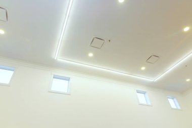 Parlak tavan ışıkları geniş odayı aydınlatıyor, temiz çizgiler sergiliyor, modern iç tasarım..