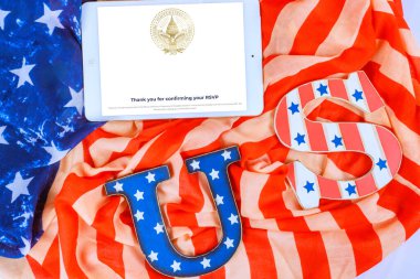 8 Ocak 2025 Washington DC ABD Tableti, ABD Başkan Yardımcısı Donald J. Trump 'ın resmi yemin töreni için hazırlanmış Amerikan bayrağı ve dekoratif mektuplarla çevrili bir RSVP onayı gösterdi.