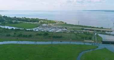 Yat limanında, yemyeşil alanlar ve açık gökyüzüyle çevrili çok sayıda tekne yer alıyor..