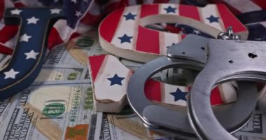 Kelepçe, dolar banknotları ve kırmızı, beyaz ve mavi harflerin yakın çekimi bir Amerikan temasını vurguluyor..