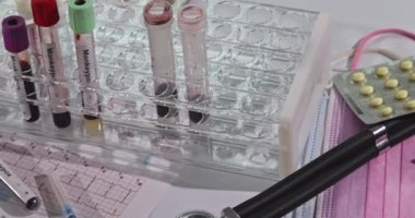 Çeşitli test tüpleri ve tıbbi gereçler bir laboratuvar masasına yerleştirildi. Kan testi prosedürleri için hazırlar..