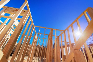 Parlak mavi gökyüzüne karşı yükselen ahşap çerçeveler gibi yeni binalar inşa eden kirişler.