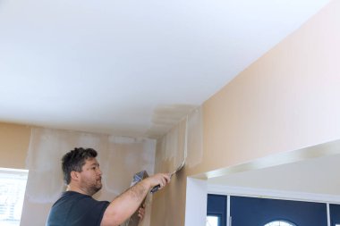 İşçi, temiz iç odadaki tavana özenle boya uyguluyor.