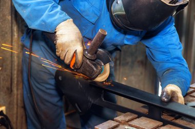 Becerikli zanaatkar atölyedeki aletleri kullanarak çeliği öğütür, kıvılcımlar yaratır, pürüzsüz bir son sağlar.