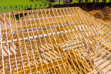 Çalışma alanındaki inşaat sahasında çatı yapısı oluşturmak için tahta kirişler monte ediliyor.