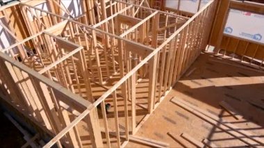 İşçiler, açık mavi gökyüzünün altında yeni ev için ahşap iskelet dikmekle meşguller..