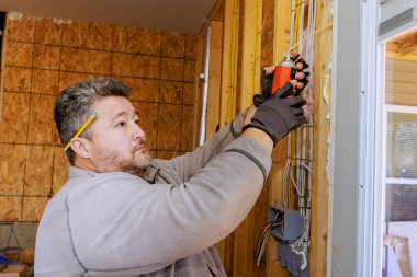 Marangoz kısmen inşa edilmiş bir odada kapı çerçevesine su geçirmez sprey sıkar..