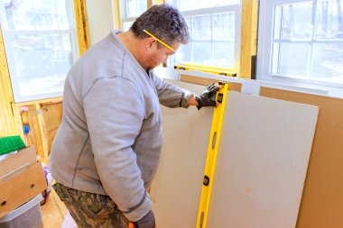 Çalışmalarında alçı taşı ile çevriliyken seviye aracı kullanan işçiler