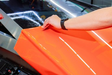 Otomotiv atölyesinin modern görünümünü korumak için arabanın yüzeyine vinil ambalaj yumuşak bir şekilde uygulanmaktadır..