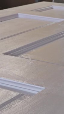 Bir kapı düz bir çalışma alanında duruyor, yakın zamanda parlak bir bitirme ile boyanmış araçlar yakınlarda görünür iken.