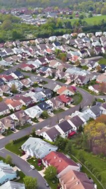 Hava perspektifi, ilkbaharda evler, ağaçlar ve kıvrımlı yollarla huzurlu bir banliyö bölgesi gösteriyor..