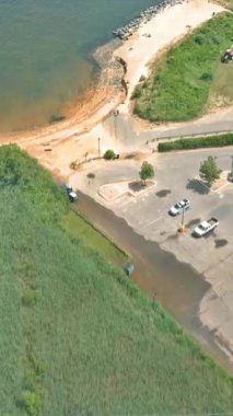 Havadan bakıldığında kumlu sahil girişi olan sakin bir göl ve çevresi yeşilliklerle çevrili bir otopark görünüyor..