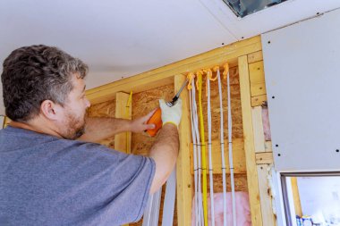 Müteahhit kısmen yenilenmiş odadaki ahşap çerçevelere sprey köpük macunu sürmekle meşgul.