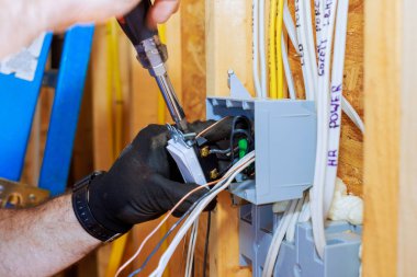 Elektrik işçisi evdeki yeni elektrik prizi kurulumuna kablolar bağlıyor