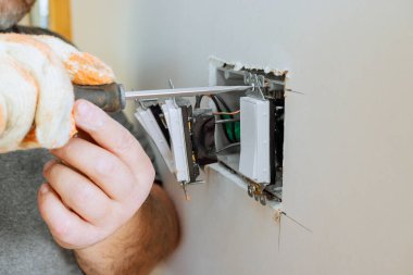 Marangoz ev onarımı sırasında duvarın içindeki elektrik düğmelerini tamir ediyor.