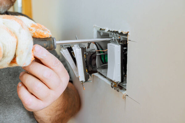 Carpenter is fixing electrical switches inside wall during home repair