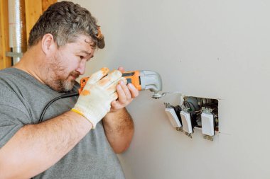 Elektrikçi ev yenileme işlerinde duvara elektrik düğmeleri takmak için ustalıkla elektrikli araç kullanıyor