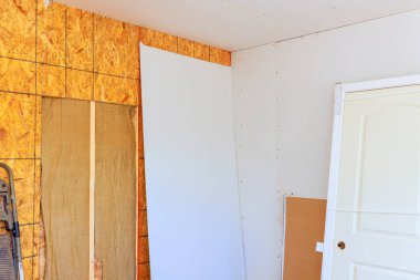 Duvara yaslanmış tamamlanmamış duvar, ahşap paneller, devam eden inşaat çalışmalarını gösteren.