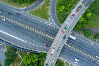 Araçlar, New Jersey 'deki Amerikan kasabası yakınlarındaki yeşil alanlarla çevrili karmaşık otoyol kavşağından geçiyor.