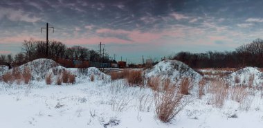 Güneş doğarken kar örtüleri tepeciklerini örterek demiryolu yakınlarındaki kış manzarasında sıcak renkler bırakıyor.
