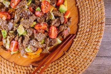 Canlı kızarmış biftek ve taze sebzeler, üstüne de bambu tabakta susam tohumları..