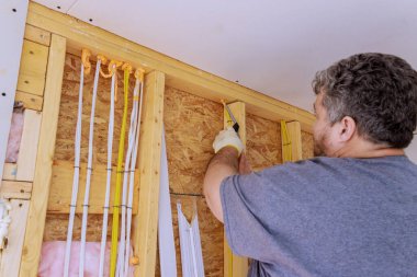 İşçi köpük yalıtımı uyguluyor. Enerji verimliliğinin artırılması için ev yenilenmesinde elektrik kabloları hazırlıyor..