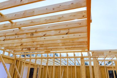 İşçiler çatı kerestesiyle çevrili inşaat sahasında ahşap kirişler kuruyorlar.