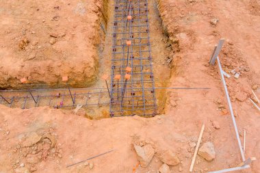 İşçiler inşaat projesinde beton temeller için çelik takviyeli siper hazırlıyorlar.