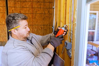 İşçi inşaat alanına su geçirmez köpük yerleştirirken güvenlik için eldiven takıyor..