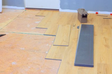Worker manage flooring materials while preparing to install laminate planks in home renovation